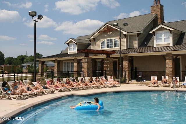 back of property with a community pool, a pergola, and a patio area