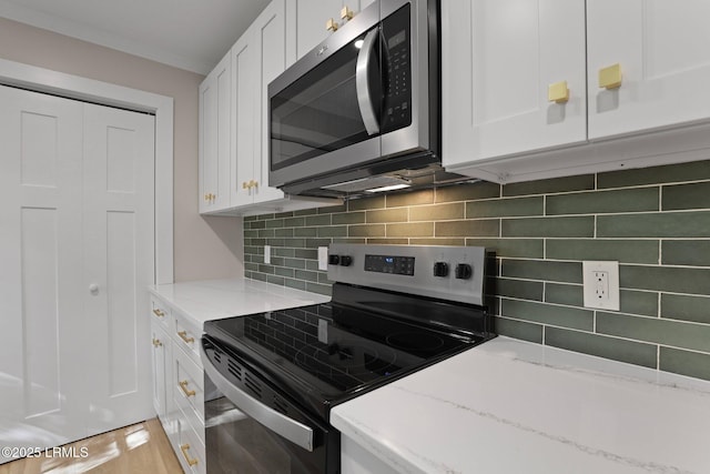 kitchen with appliances with stainless steel finishes, tasteful backsplash, light stone counters, white cabinets, and light wood finished floors