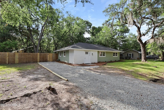 view of front of house featuring fence, driveway, and a front lawn
