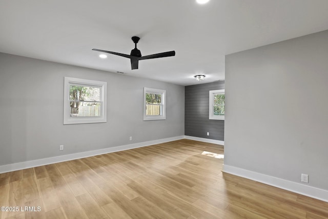 spare room featuring baseboards, plenty of natural light, and light wood-type flooring