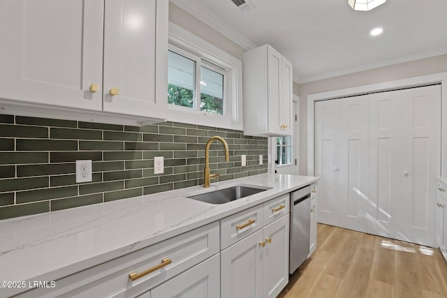 kitchen featuring a sink, white cabinetry, tasteful backsplash, stainless steel dishwasher, and ornamental molding