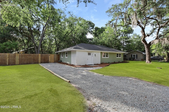 view of front facade with fence, a shingled roof, driveway, and a front lawn