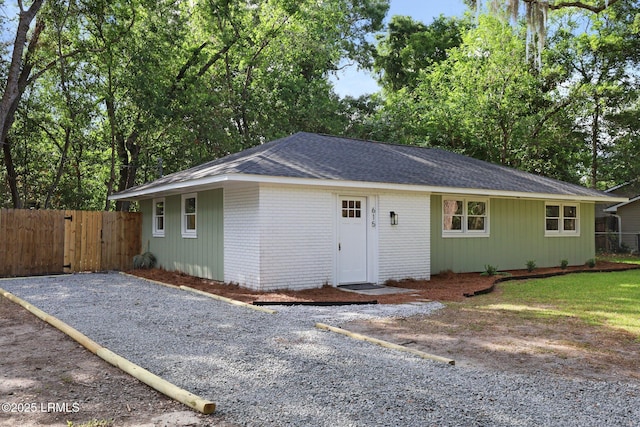 view of front of property with brick siding, a gate, roof with shingles, and fence
