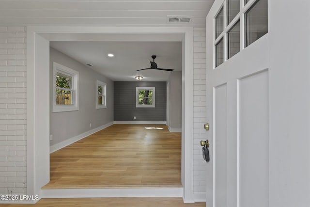 interior space with light wood-type flooring, baseboards, ceiling fan, and visible vents