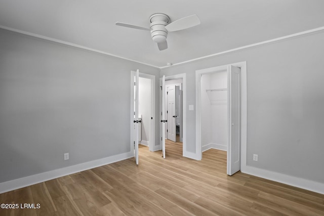 unfurnished bedroom featuring crown molding, ceiling fan, baseboards, light wood-type flooring, and a closet