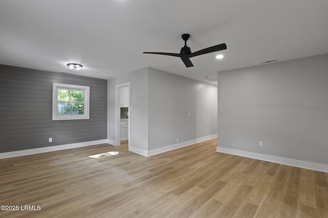 empty room with baseboards, visible vents, ceiling fan, and light wood finished floors
