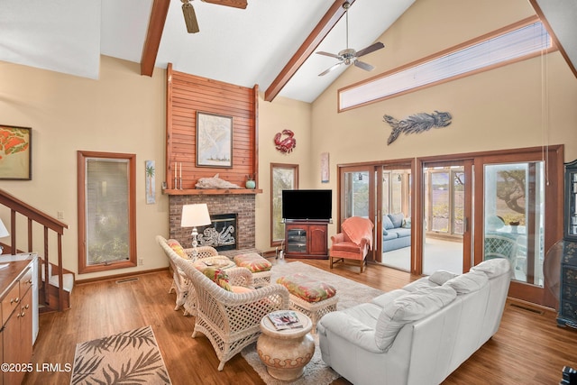living area with high vaulted ceiling, ceiling fan, beamed ceiling, and a brick fireplace