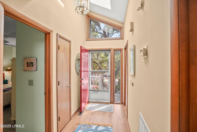 doorway with a high ceiling, light wood-style flooring, and visible vents