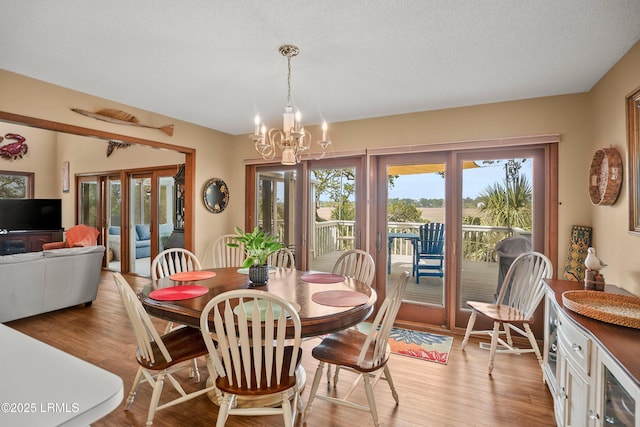 dining area with an inviting chandelier, light wood-style floors, wine cooler, and french doors