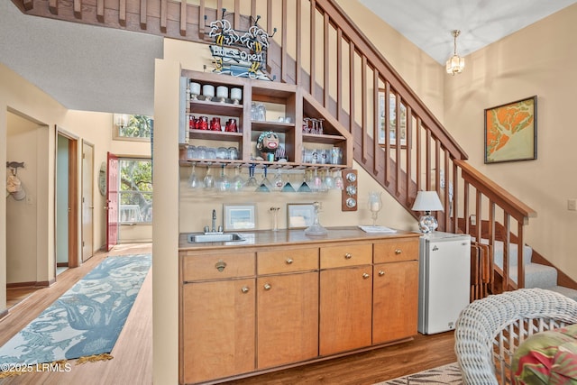 stairs featuring wood finished floors and bar area