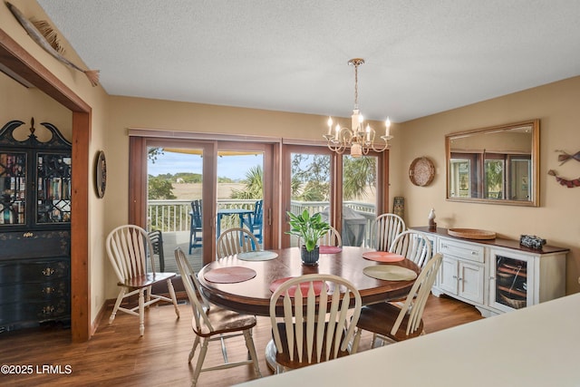 dining area with a textured ceiling, wood finished floors, and a chandelier