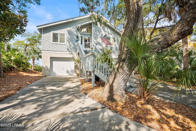 view of front of property with concrete driveway, stucco siding, stairs, and a garage
