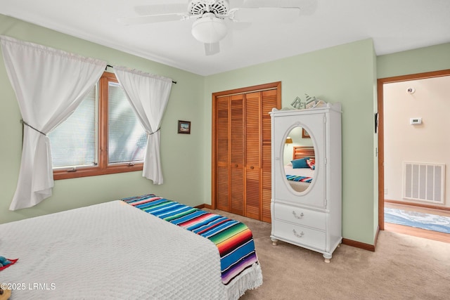 bedroom featuring visible vents, a closet, baseboards, light colored carpet, and a ceiling fan