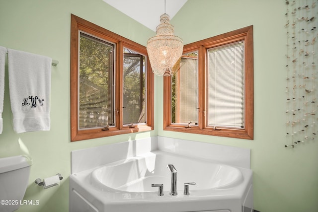 bathroom with vaulted ceiling, a bath, a chandelier, and toilet