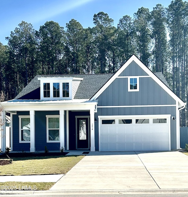 view of front of property featuring roof with shingles, an attached garage, board and batten siding, a front yard, and driveway