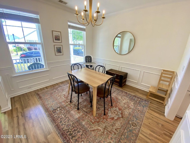 15 6th Ave, Bluffton, SC 29910 - dining area featuring a chandelier, wood finished floors, a decorative wall, crown molding, and wainscoting