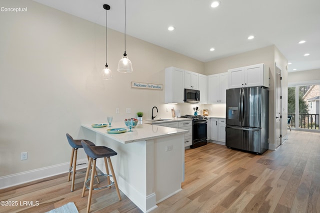 kitchen featuring sink, stainless steel appliances, white cabinets, decorative light fixtures, and kitchen peninsula