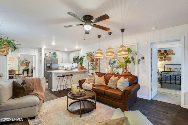 living room featuring ceiling fan, dark hardwood / wood-style floors, and sink