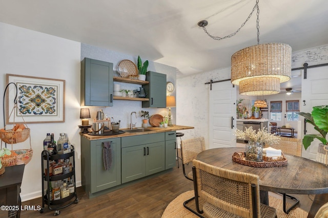 kitchen with green cabinets, a barn door, a sink, and dark wood-style floors