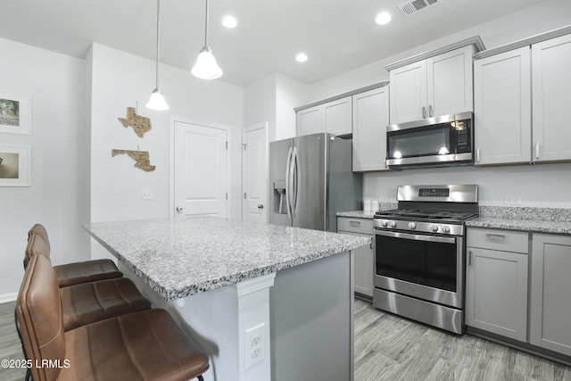 74 Keowee Ln, Beaufort, SC 29906 - kitchen with stainless steel appliances, gray cabinetry, light wood-style floors, a kitchen island, and a kitchen breakfast bar