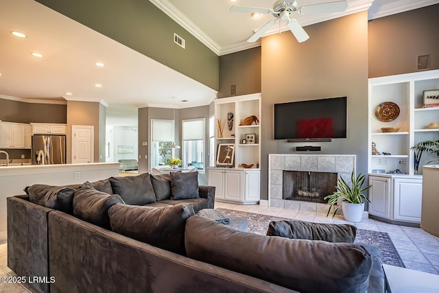 1348 Rowland Dr, Saint Helena Island, SC 29920 - tiled living room featuring a tiled fireplace, crown molding, a towering ceiling, and ceiling fan