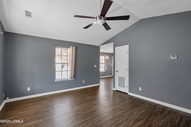 empty room featuring ceiling fan with notable chandelier, dark hardwood / wood-style floors, and vaulted ceiling