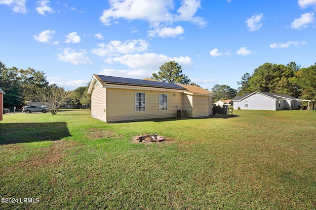 view of property exterior featuring a lawn, solar panels, and central air condition unit