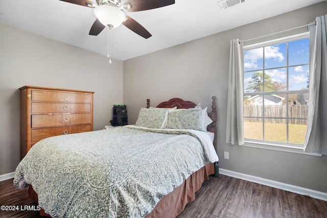 bedroom featuring multiple windows, dark wood-type flooring, and ceiling fan