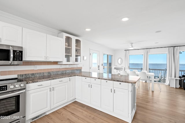 108 Harbor Dr N, Harbor Island, SC 29920 - kitchen featuring stainless steel appliances, dark stone countertops, ceiling fan, glass insert cabinets, and a peninsula
