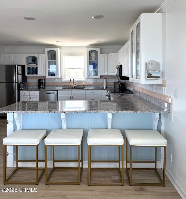 108 Harbor Dr N, Harbor Island, SC 29920 - kitchen featuring stainless steel appliances, a peninsula, a sink, light stone countertops, and glass insert cabinets