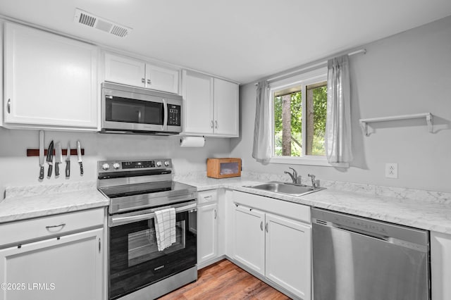 7058 Roseida Rd, Beaufort, SC 29906 - kitchen featuring appliances with stainless steel finishes, white cabinets, open shelves, light wood finished floors, and light stone counters