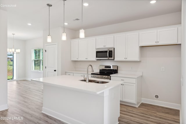 kitchen featuring pendant lighting, sink, stainless steel appliances, white cabinets, and a center island with sink