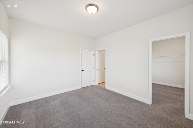 unfurnished bedroom with a walk in closet and carpet