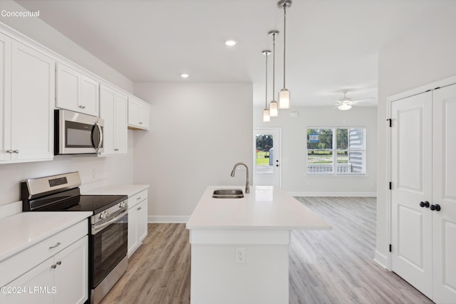 kitchen featuring sink, white cabinetry, pendant lighting, stainless steel appliances, and a kitchen island with sink