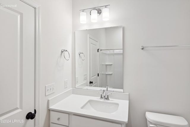 bathroom featuring walk in shower, vanity, and toilet