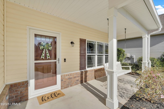 doorway to property with brick siding and covered porch