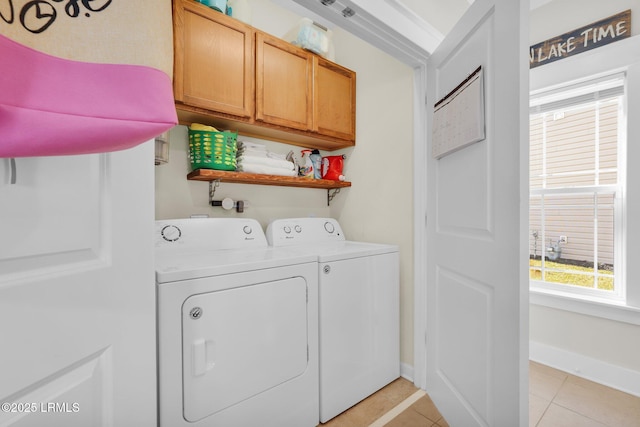 laundry area with light tile patterned floors, cabinet space, baseboards, and separate washer and dryer