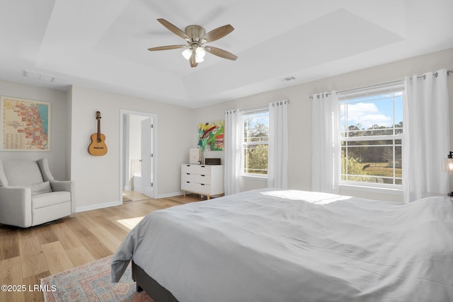 bedroom featuring visible vents, ceiling fan, baseboards, light wood-style floors, and a raised ceiling