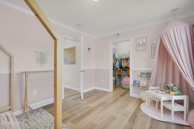 rec room featuring light wood-style floors, baseboards, and ornamental molding