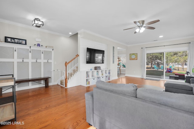 living room with stairway, ornamental molding, a ceiling fan, and wood finished floors