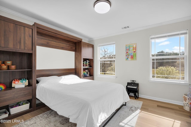 bedroom featuring crown molding, light wood-style flooring, visible vents, and baseboards