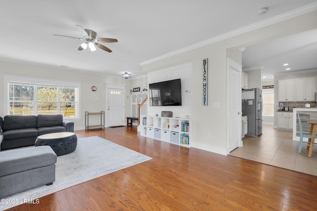 living room featuring a wealth of natural light, light wood-style flooring, a ceiling fan, and ornamental molding