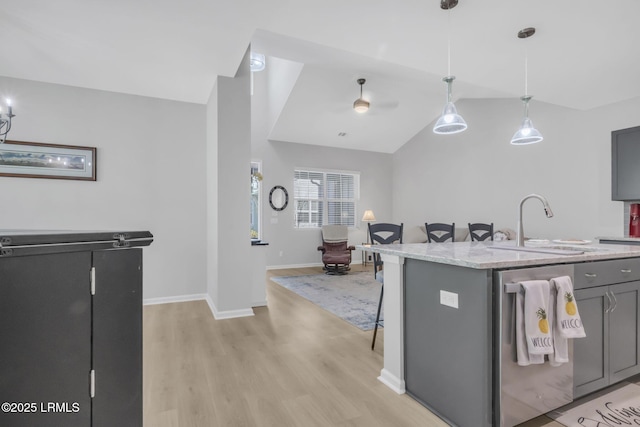 kitchen featuring sink, gray cabinets, a kitchen island with sink, hanging light fixtures, and vaulted ceiling