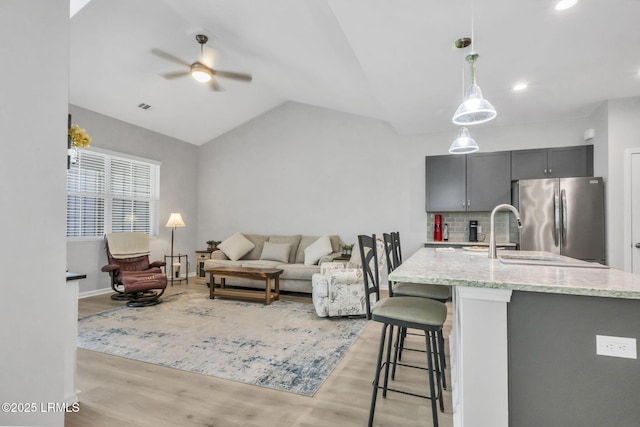 living room featuring sink, vaulted ceiling, light hardwood / wood-style floors, and ceiling fan