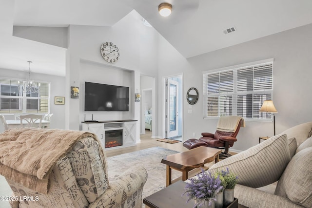 living room featuring an inviting chandelier, high vaulted ceiling, and light hardwood / wood-style floors