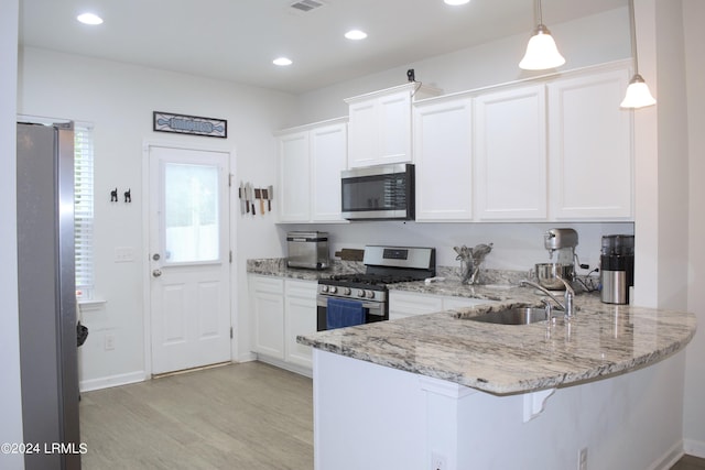 kitchen featuring sink, appliances with stainless steel finishes, kitchen peninsula, pendant lighting, and white cabinets