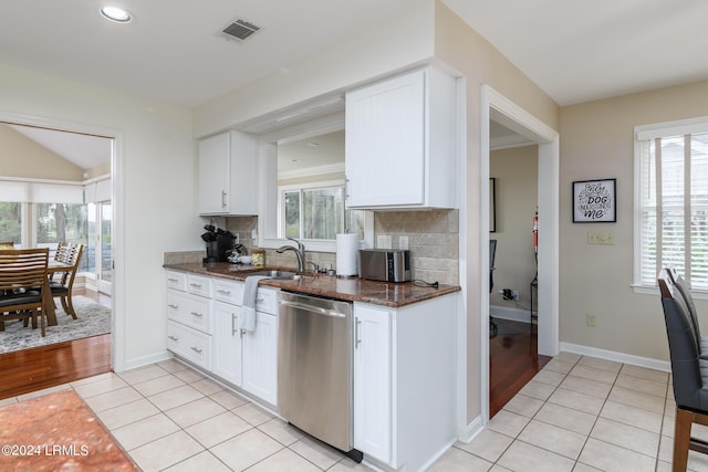 kitchen featuring sink, light tile patterned floors, backsplash, stainless steel dishwasher, and white cabinets