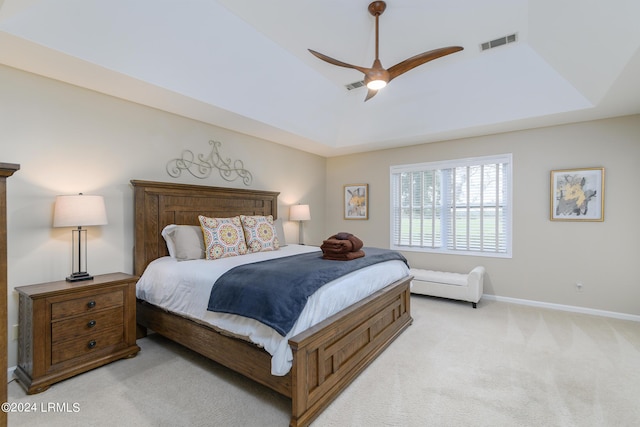 carpeted bedroom with a tray ceiling and ceiling fan