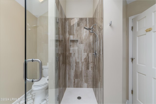 bathroom featuring a shower with door and toilet