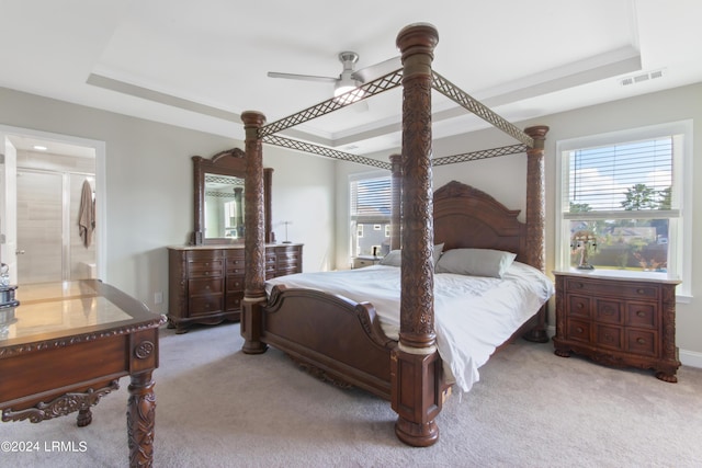 carpeted bedroom featuring ensuite bath, a raised ceiling, and ceiling fan